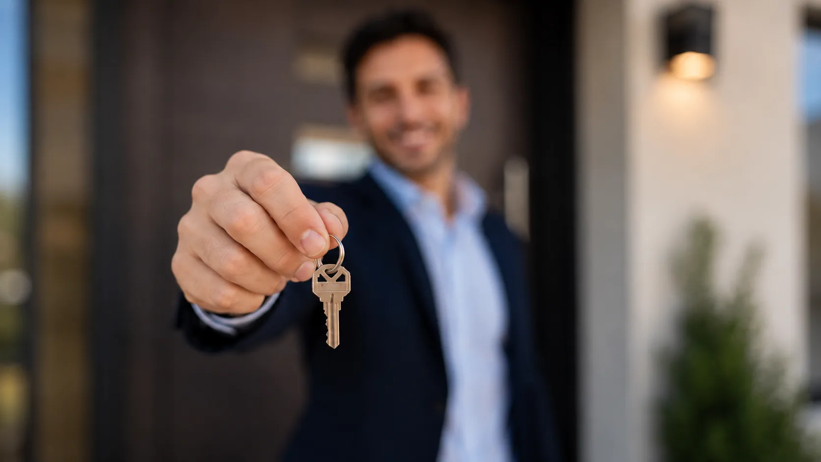 Estate agent with keys in front of a residential property